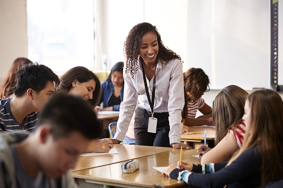 OSBA Program - Elementary School Teacher Giving Pupil One To One Support In Classroom